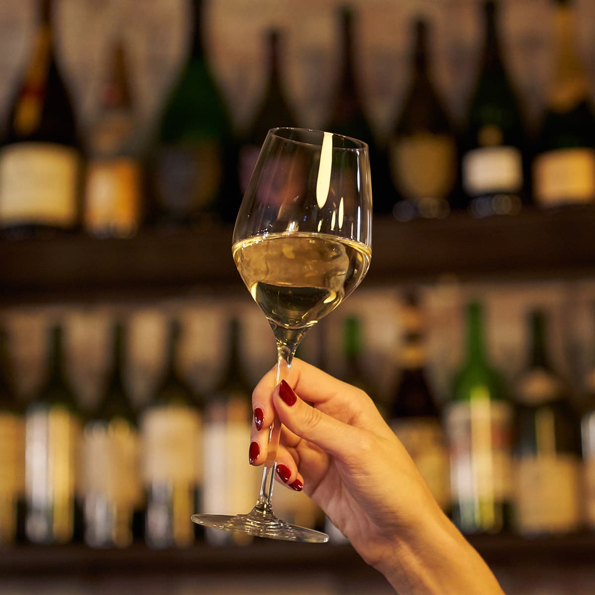 Holding a glass of wine up in order to visually survey the wine before drinking it.
