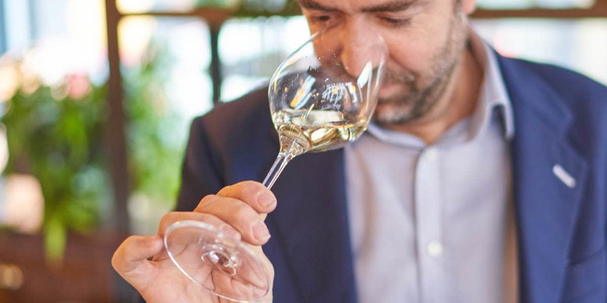 Smelling the nose of a glass of wine.
