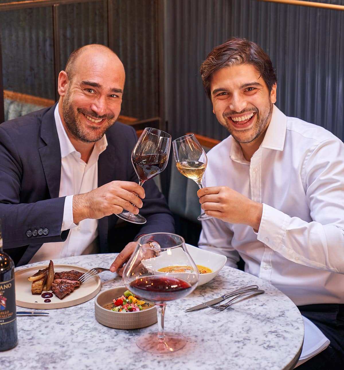 A couple of gentlemen toasting an excellent food and wine pairing.