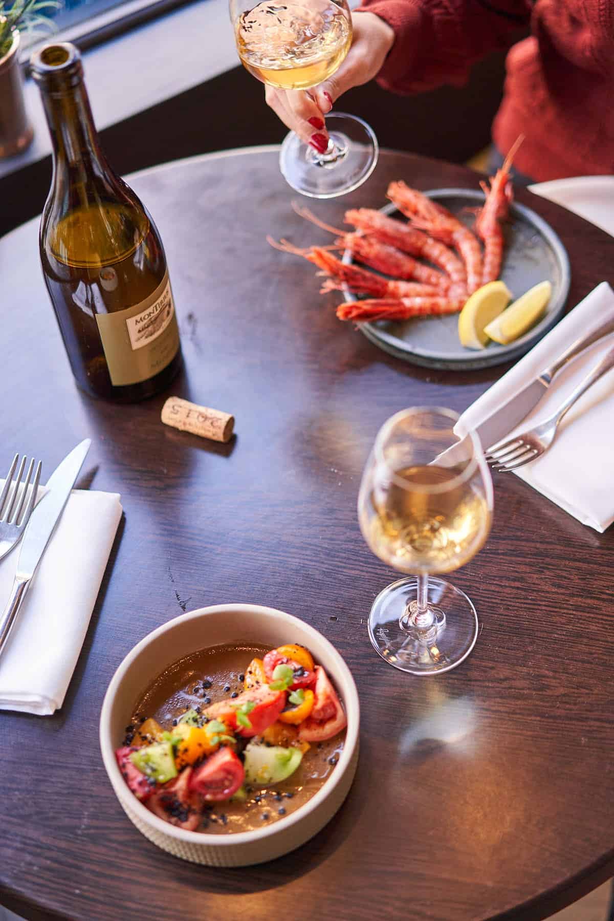 Glasses of wine with a plate of salad and a plate of seafood.