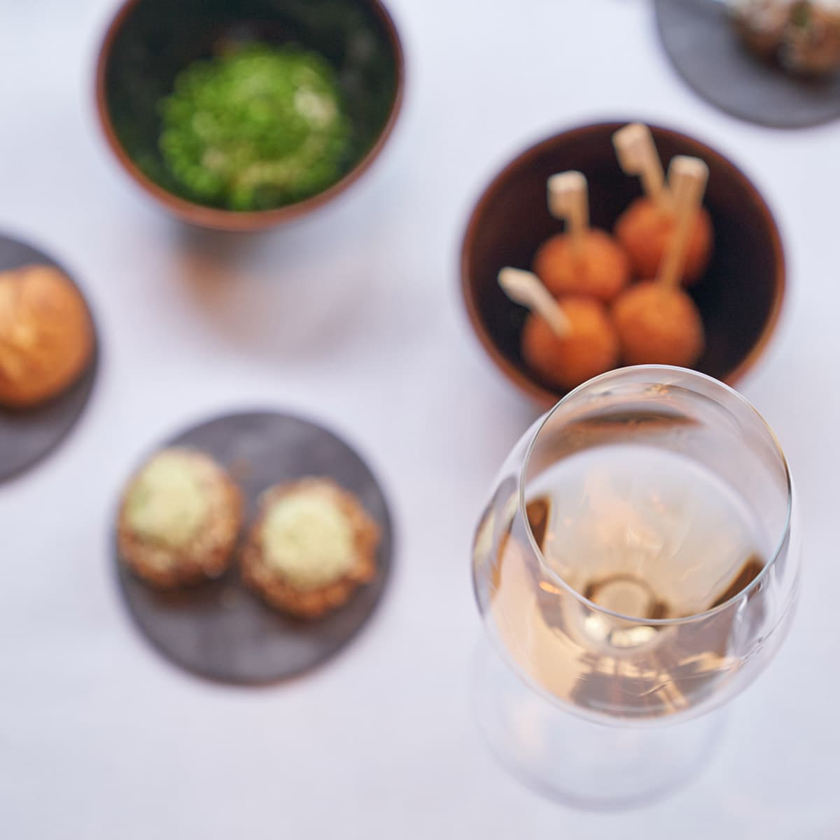 A glass of wine with several snacks and finger foods.